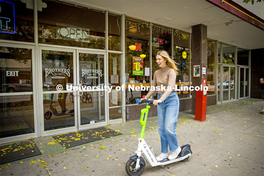 Emma Dostal rids a Lime e-scooter in downtown Lincoln. About Lincoln with the Lime Scooter e-Scooter program. October 18, 2023. Photo by Kristen Labadie / University Communication.